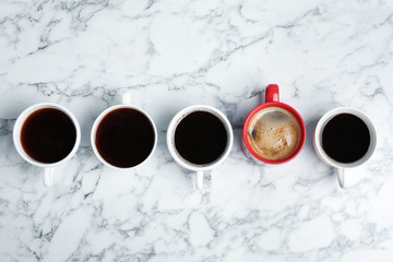 Cups of coffee and different one on marble background, top view