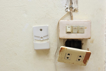a light switch and electrical socket switch with damaged wiring on the wall