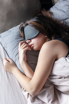 The girl in a sleep mask is resting in her bed. Beautiful tinted photo.
