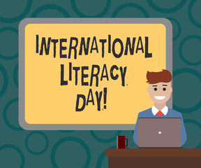 Writing note showing International Literacy Day. Business photo showcasing Celebrated annual event on 8 of September Bordered Board behind Man Sitting Smiling with Laptop Mug on Desk