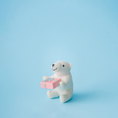 Polar bear toy with Christmas gift box on bright pastel blue background. Christmas and winter holidays concept.
