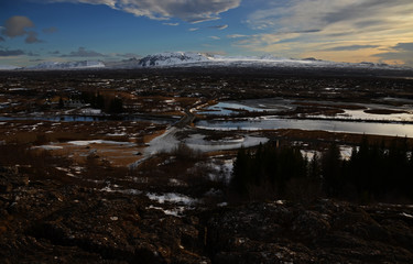 Typical Icelandic landscape: Thingvellir National Park, rivers, lava fields covered with snow against the backdrop of mountains and sky