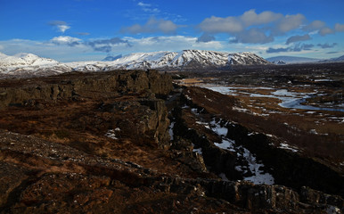 Typical Icelandic landscape: Thingvellir National Park, rivers, lava fields covered with snow against the backdrop of mountains and sky
