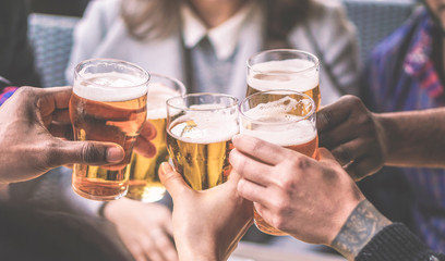 Groep vrienden genieten van een bierglazen in brouwerij Engelse pub - Jongeren juichen in bar-restaurant - Vriendschap en jeugdconcept - Warm vintage filter - Hoofdfocus op linker zwarte hand