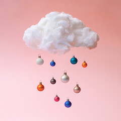 Cloud with Christmas ornaments as rain. Minimal New Year concept background.