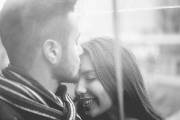 Happy couple having tender moments under umbrella during rainy day