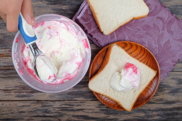 Boy hand with scoop takes ice cream and serving in a bread over an  old tabletop.