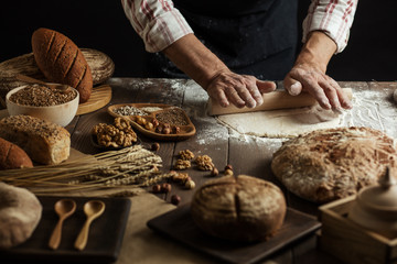 Male hands roll out dough on kitchen floured surface background with cooking background, close up. Cooking process concept.