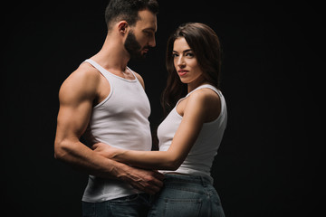 boyfriend hugging girlfriend in white singlet isolated on black