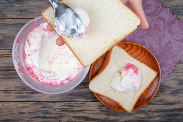 Boy hand with scoop takes ice cream and serving in a bread over an  old tabletop.
