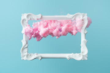 White vintage frame on pastel blue background with abstract pink cloud shapes. Minimal border...