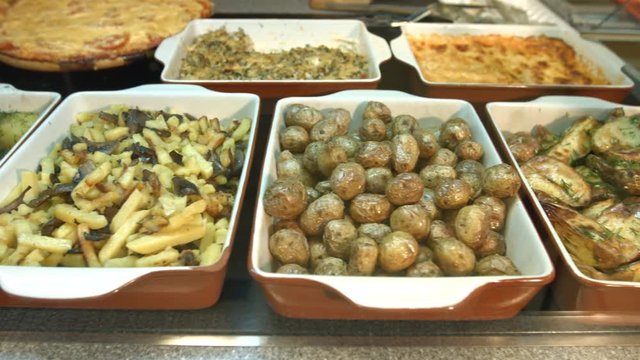 Side dishes in the supermarket.
Different side dishes are located on the showcase: fried potatoes with onions, boiled potatoes with greens, fried potatoes with mushrooms, small baked potatoes