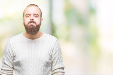 Young caucasian hipster man wearing winter sweater over isolated background puffing cheeks with funny face. Mouth inflated with air, crazy expression.