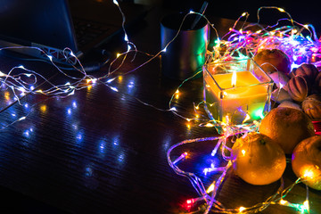 Top view. Christmas New Year Composition with Tangerines candle, garlands, colorful lights, selective focus Black Background Holiday Decoration, copy space