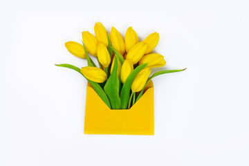 Fresh yellow spring tulips in envelope on white background, flower delivery concept, free space for text, greeting card