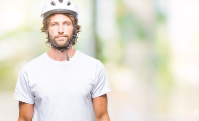 Handsome hispanic cyclist man wearing safety helmet over isolated background with serious expression on face. Simple and natural looking at the camera.