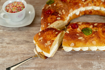 King's cake made by hand in the oven, on a cozy wooden base, and a cup with colorful chocolate stars.