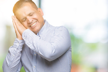 Middle age arab business man over isolated background sleeping tired dreaming and posing with hands together while smiling with closed eyes.