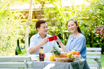 Asian Elderly couple Sitting in the home garden Rest from work throughout life taking care of health after retirement eating tea and coffee drinks appropriately Eat useful food Life insurance concept