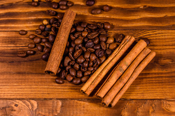 Pile of the coffee beans and cinnamon sticks on wooden table