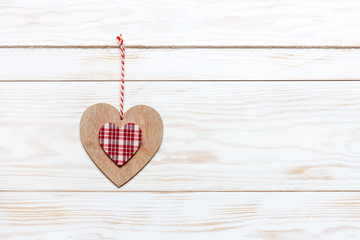 Wooden colorful heart on rope. Concept for Valentine's Day, wedding, engagement and other romantic events. Top view, close-up, flat lay on white wooden background