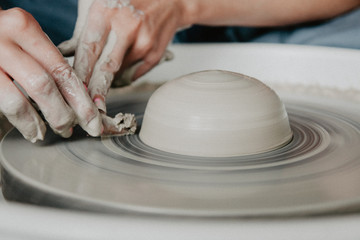 Creating a jar or vase of white clay close-up. Woman hands making clay jug.