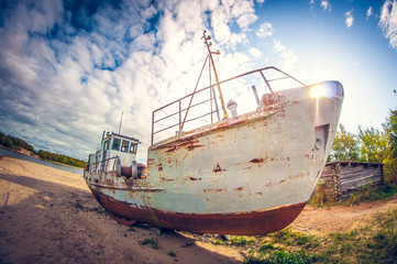 abandoned boat on the sandy shore of a lake on a sunny day. distortion perspective fisheye lens