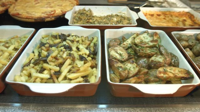 Side dishes in the supermarket.
Different side dishes are located on the showcase: fried potatoes with onions, boiled potatoes with greens, fried potatoes with mushrooms