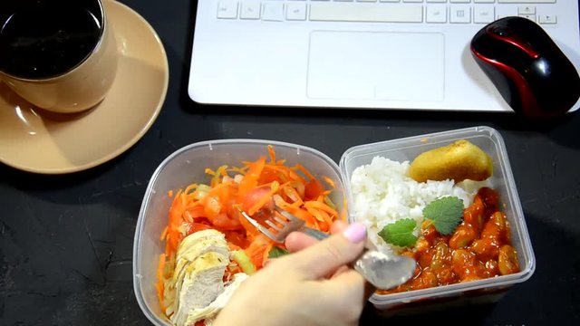 Healthy eating for lunch to work. Food in the office. The girl has lunch at the working place. The concept of food delivery to the office. The girl eats and works at the computer. Food storage in