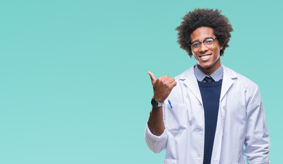 Afro american doctor scientist man over isolated background smiling with happy face looking and pointing to the side with thumb up. - obrazy, fototapety, plakaty