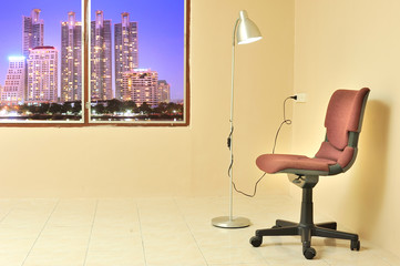 Red office chair with lamp against  light beige wall background.