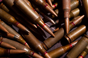 A lot of rifle ammo. AK-47 bullet cartridge. Armor piercing cartridge close up view. Underexposed photo.