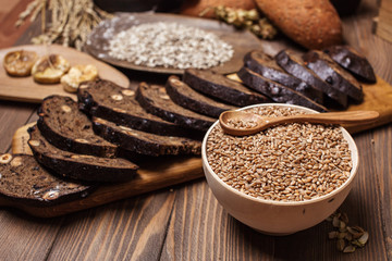 Whole grain, whole loaf and sliced pieces of multigrain bread contains whole grains ( poppy, millet, flaxseed, pumpkin seeds, and sunflower seeds) isolated on dark wooden table .