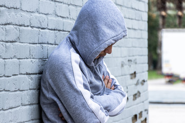 Lonely boy leaning against an urban wall