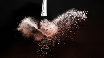 Living Coral Color des Jahres 2019, Puderspritzer und Pinsel für Maskenbildner oder Beauty-Blogger auf schwarzem Hintergrund © pariwatpannium