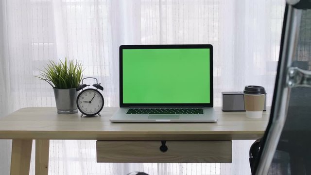 4K Green screen of laptop computer set on working space in cozy office, Zoom out shot