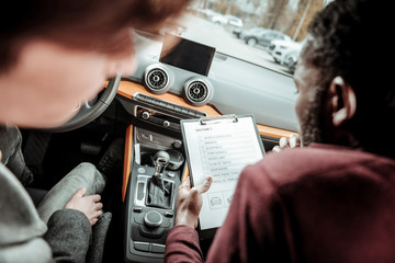 Bearded instructor putting marks for the first section of test driving