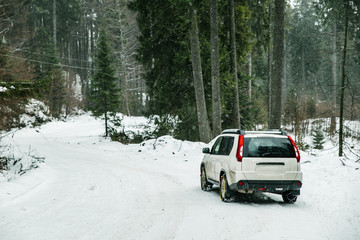 Obraz na płótnie Canvas suv car with chain on wheels in snowed forest