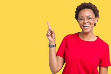 Beautiful young african american woman wearing glasses over isolated background with a big smile on face, pointing with hand and finger to the side looking at the camera.