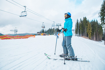 young adult woman skiing. white snowed hill with lift on background.