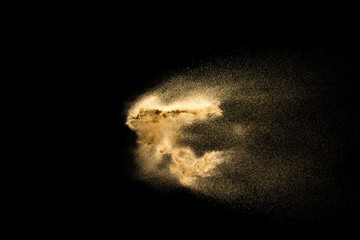 Abstract sand cloud. Golden colored sand splash against dark background.