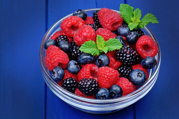 Delicious fresh berries in a bowl on wooden table