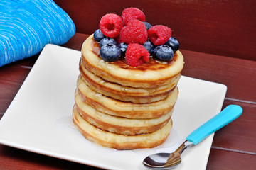 Pancakes in a plate with berries on table