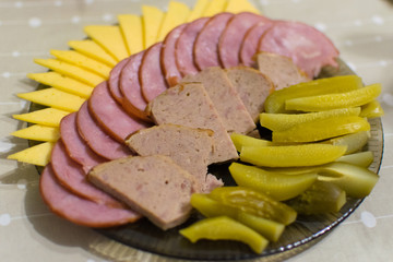 Sausage sliced and laid on a plate, cucumbers, cheese.