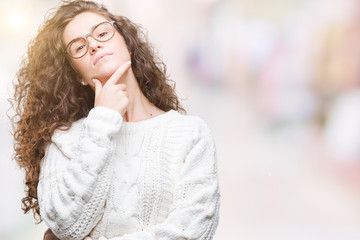 Beautiful brunette curly hair young girl wearing winter sweater over isolated background looking confident at the camera with smile with crossed arms and hand raised on chin. Thinking positive.