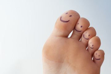 Female toes with painted smileys.