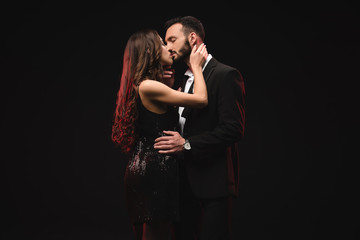 attractive sensual couple hugging and kissing isolated on black