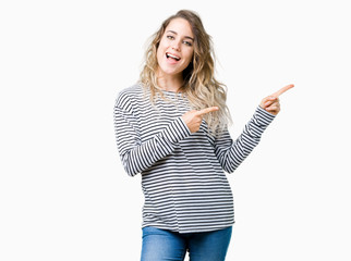 Obraz premium Beautiful young blonde woman wearing stripes sweater over isolated background smiling and looking at the camera pointing with two hands and fingers to the side.