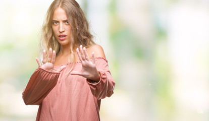 Beautiful young blonde woman over isolated background afraid and terrified with fear expression stop gesture with hands, shouting in shock. Panic concept.
