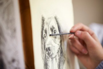 Close Up Of Artist Sitting At Easel Drawing Picture Of Dog In Charcoal